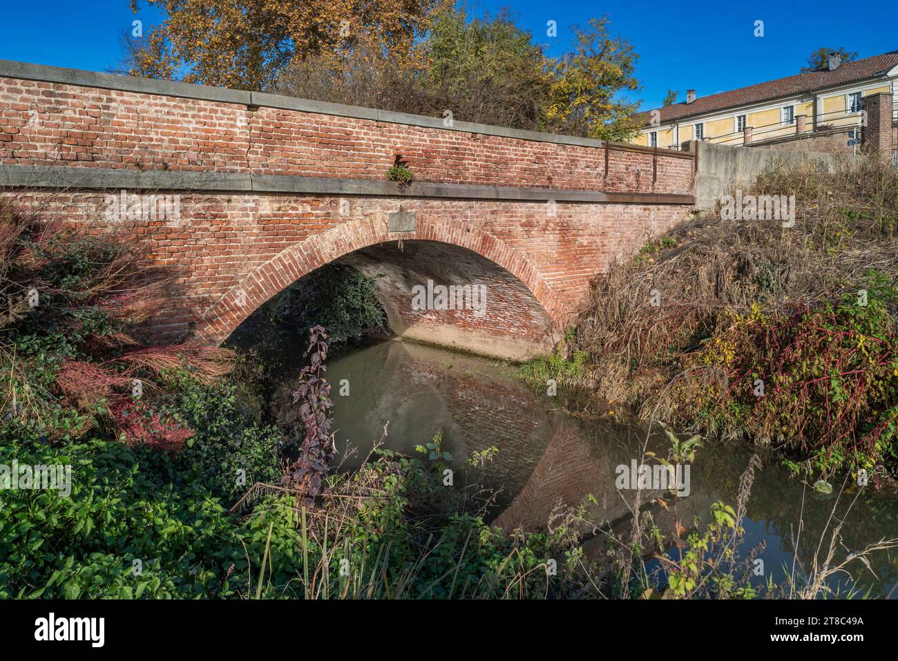 Ancien pont en brique voûté, construit en 1839, sur le canal dans la campagne de la vallée du Pô à Borgo Cornarese di Villastellone, Turin, Italie Banque D'Images