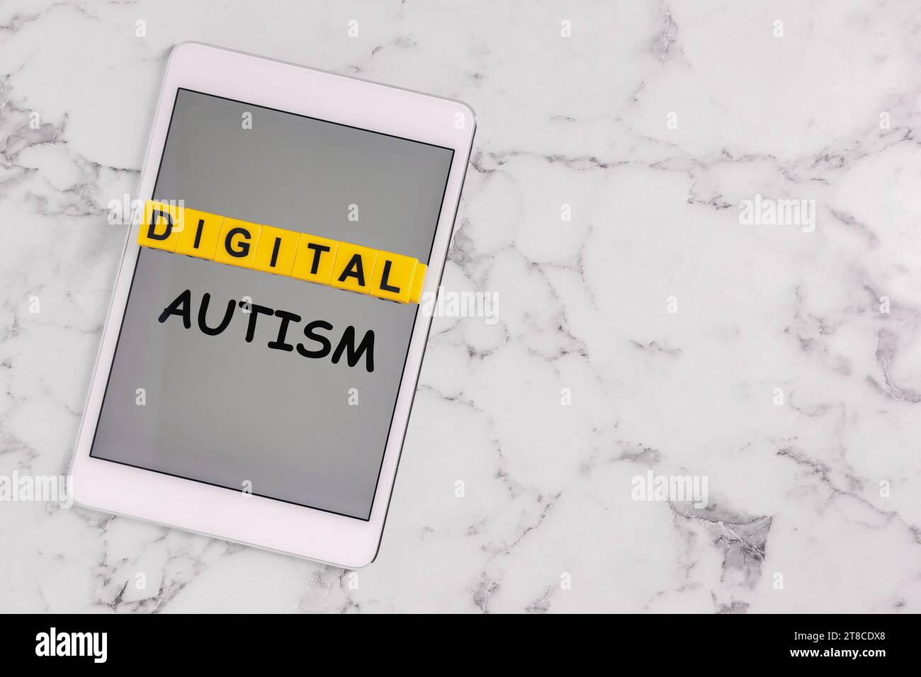 Comportement addictif. Phrase Digital Autism fait de cubes jaunes et tablette sur table en marbre blanc, vue de dessus. Espace pour le texte Banque D'Images