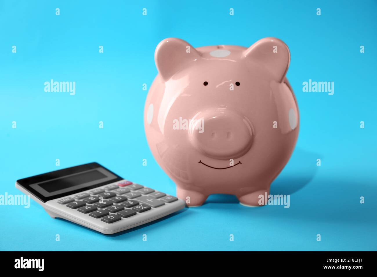 Calculatrice et tirelire rose sur fond bleu clair Banque D'Images