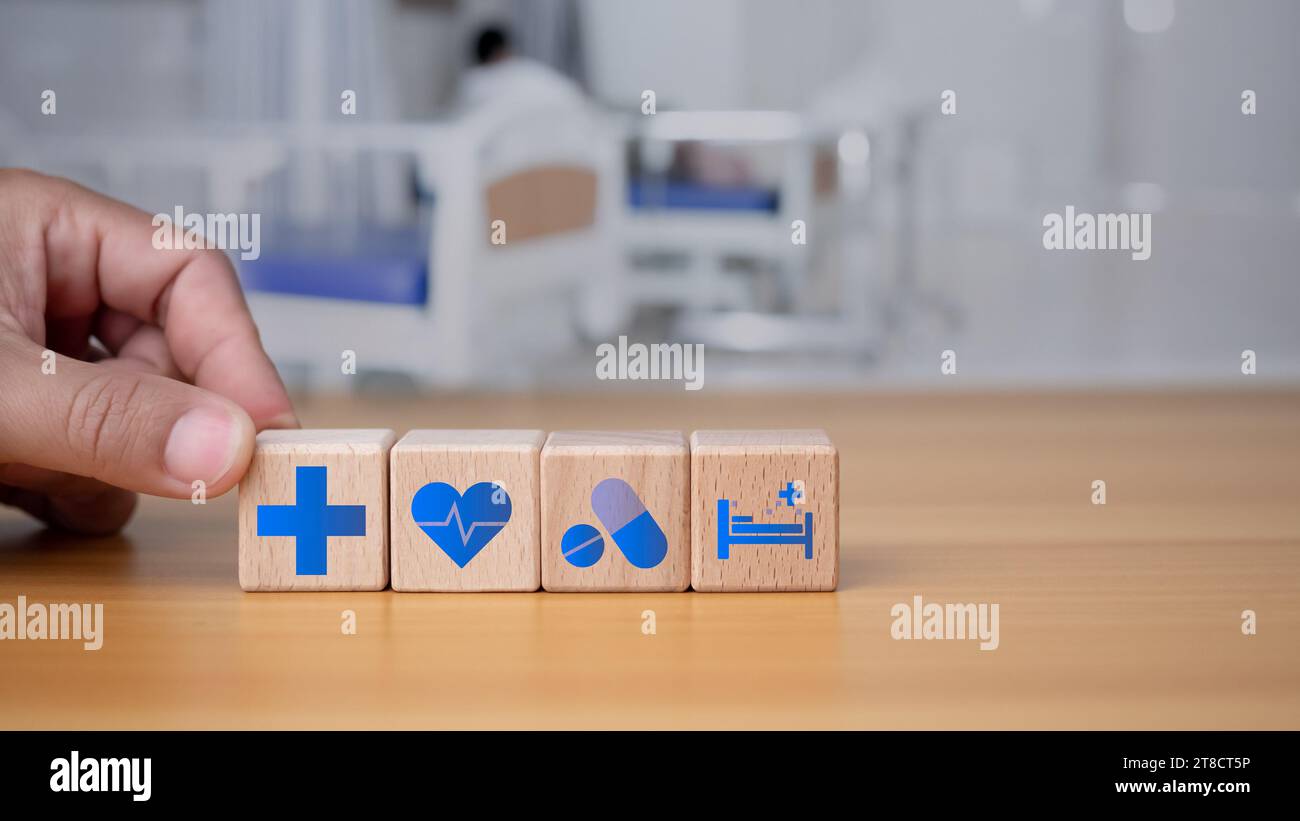 Santé et concept médical Human Hand tient un bloc de bois avec des icônes sur la santé et l'accès aux traitements, aux médicaments et aux fournitures sur un backgro bleu Banque D'Images