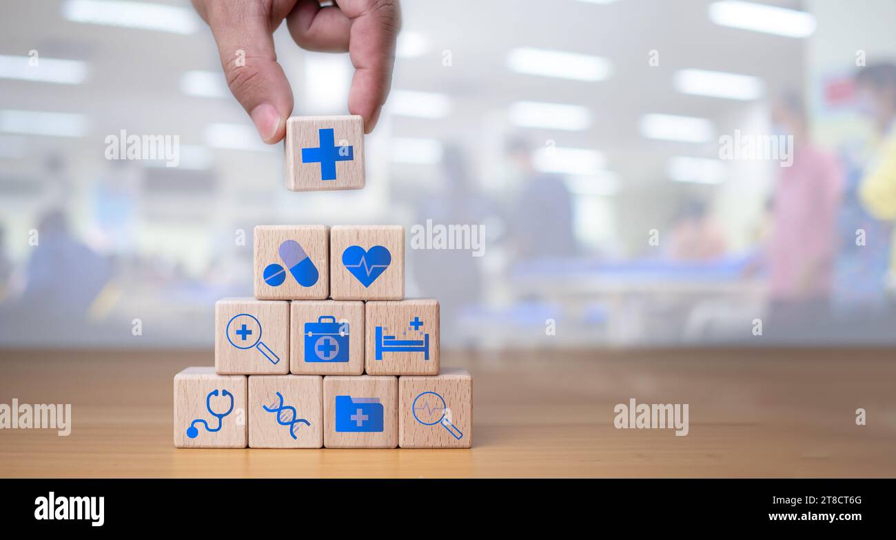 Assurance santé et concept de soins de santé, la main humaine tient le bloc de bois avec des icônes sur l'assurance santé et l'accès aux soins de santé, la planification de la retraite sur Banque D'Images