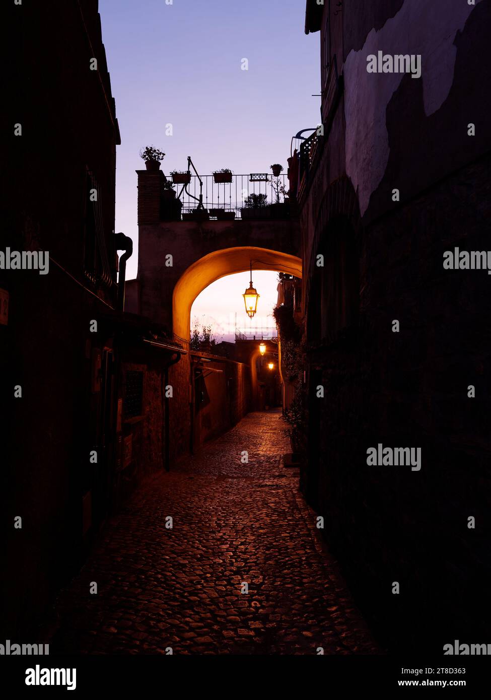 Lampadaire une rue étroite pavée avec une arche au crépuscule dans le centre historique de Montefiascone, région du Latium, Italie. 19 novembre 2023 Banque D'Images