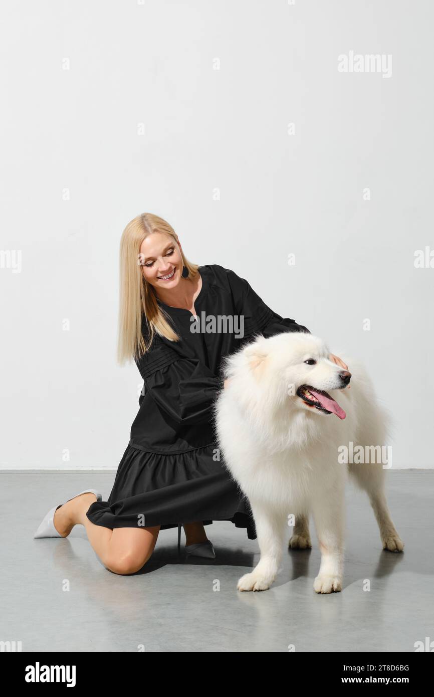 Heureuse femme blonde jouant avec son chien samoyed Banque D'Images