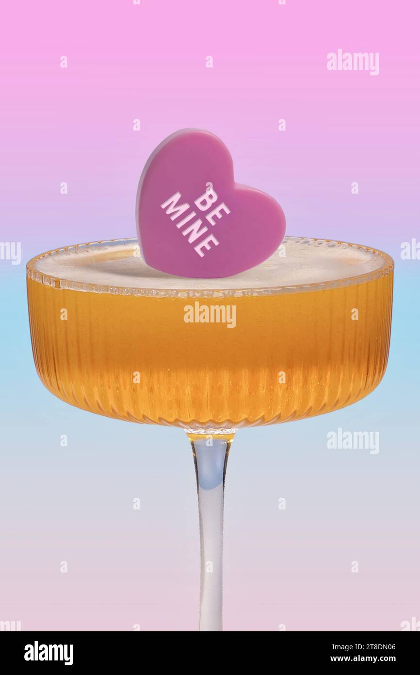 Célébration au champagne sur le thème de l'amour - bonbon cœur « Be Mine » sur une boisson pétillante pour des événements romantiques Banque D'Images