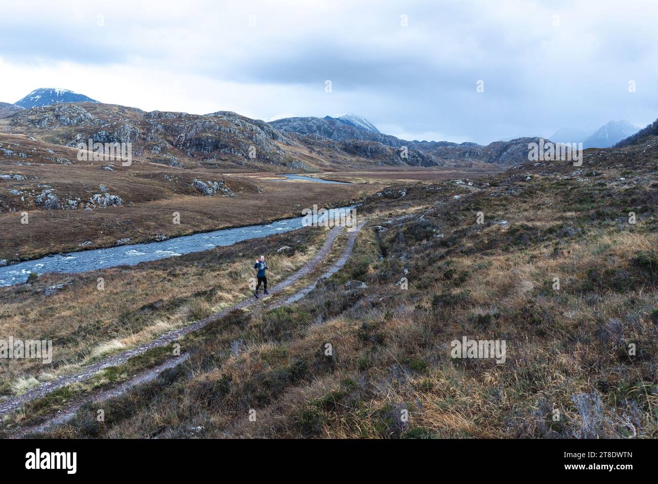 Sentier de femme courant sur un chemin de terre dans les montagnes Banque D'Images