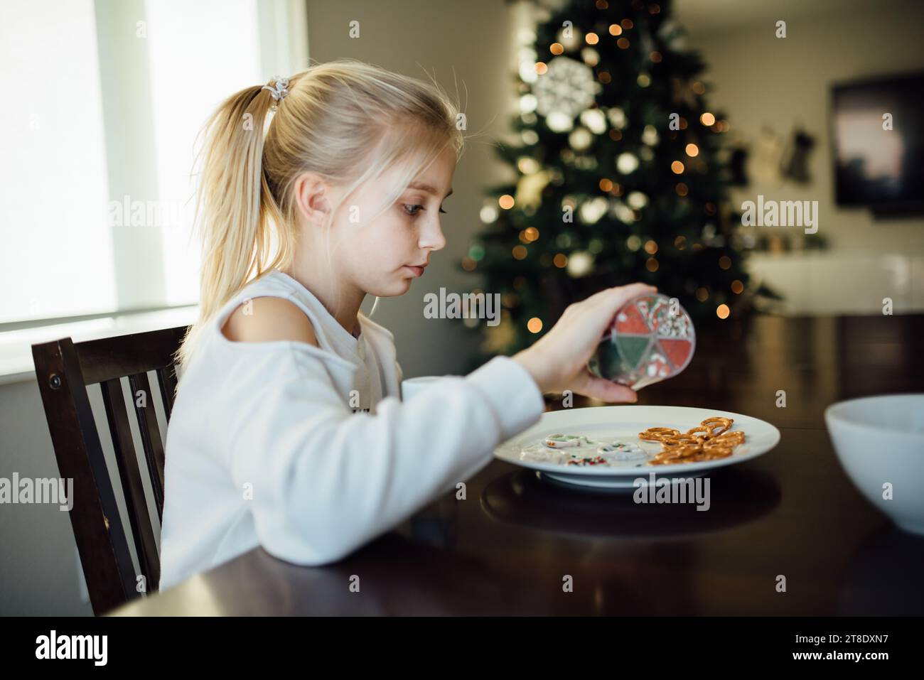 Vue latérale de l'adolescente décorant des friandises de noël avec saupoudrer Banque D'Images