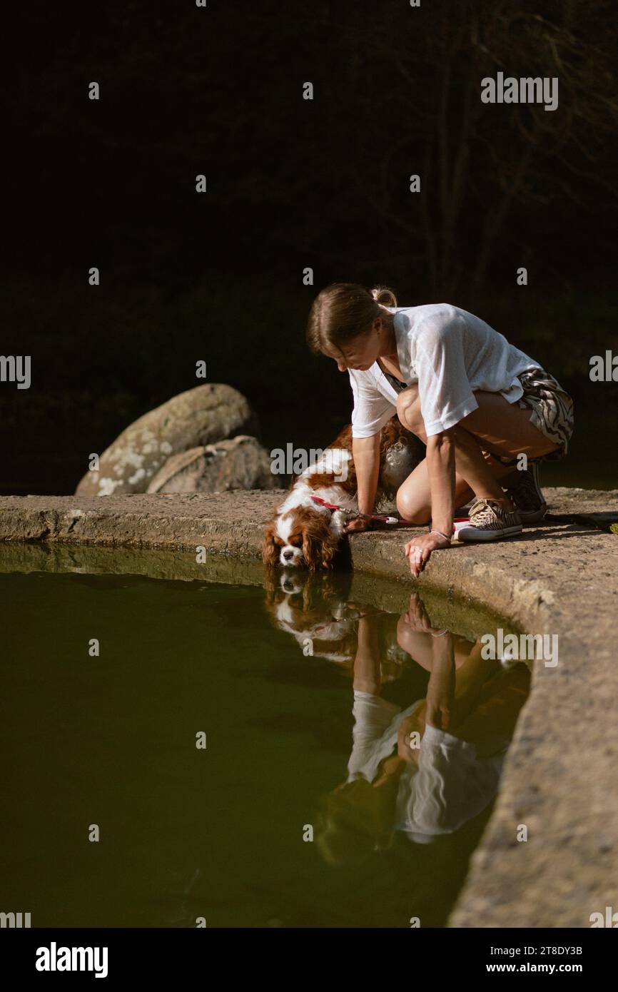Jeune femme marchant avec un chien, cavalier Charles. Banque D'Images