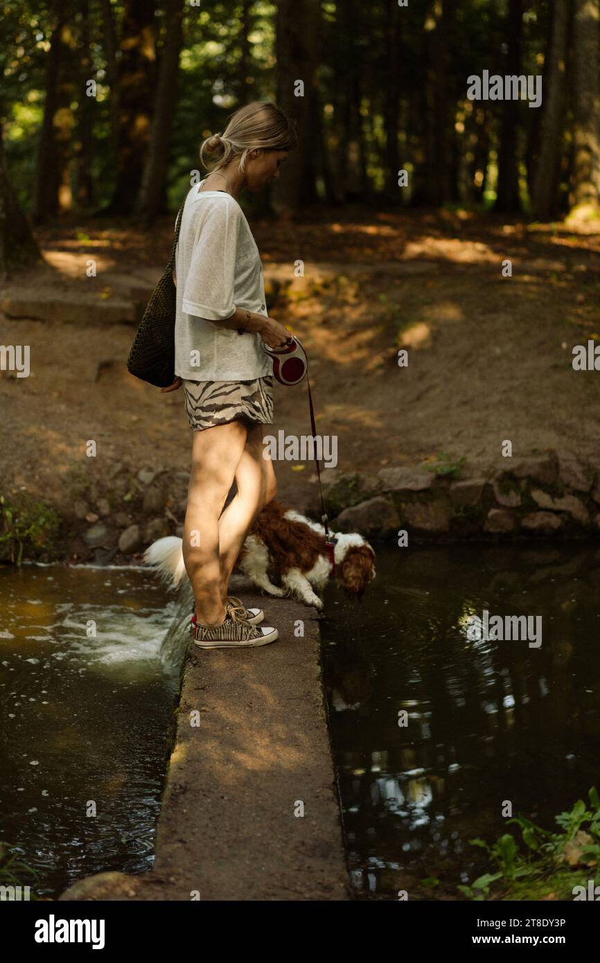 Jeune femme marchant avec un chien, cavalier Charles. Banque D'Images