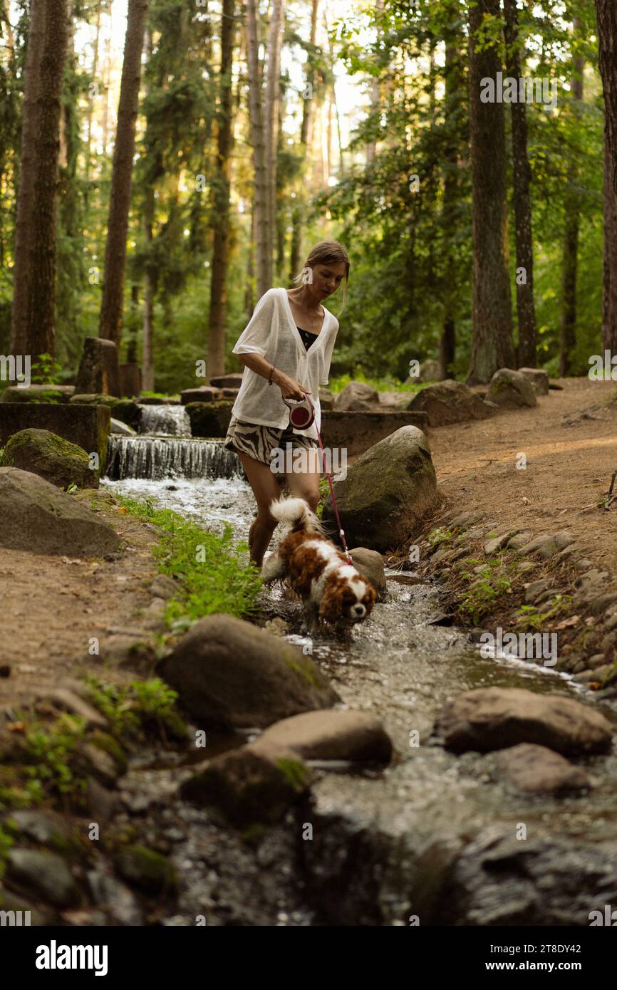 Jeune femme marchant avec un chien, cavalier Charles. Banque D'Images