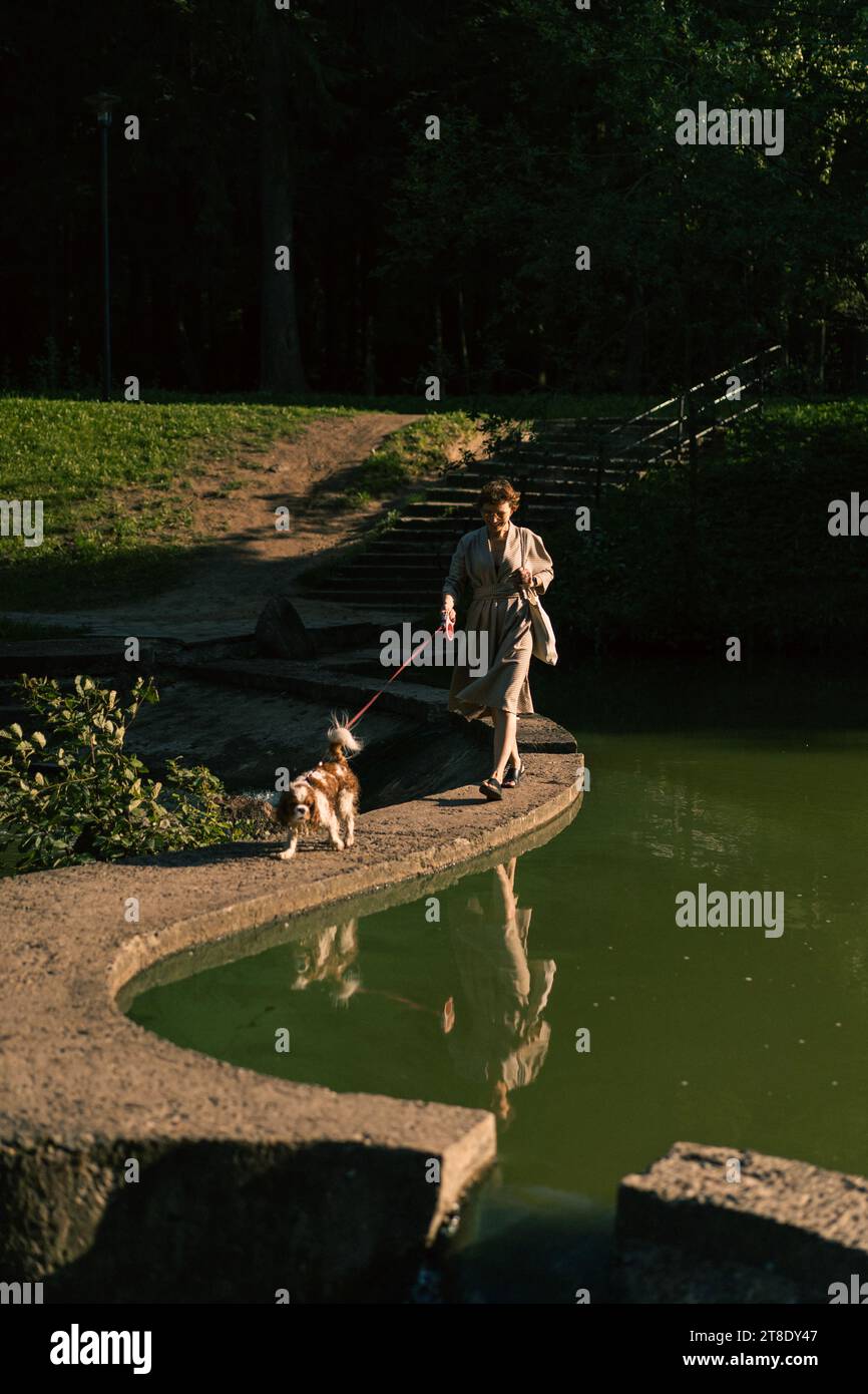 Jeune femme marchant avec un chien, cavalier Charles. Banque D'Images