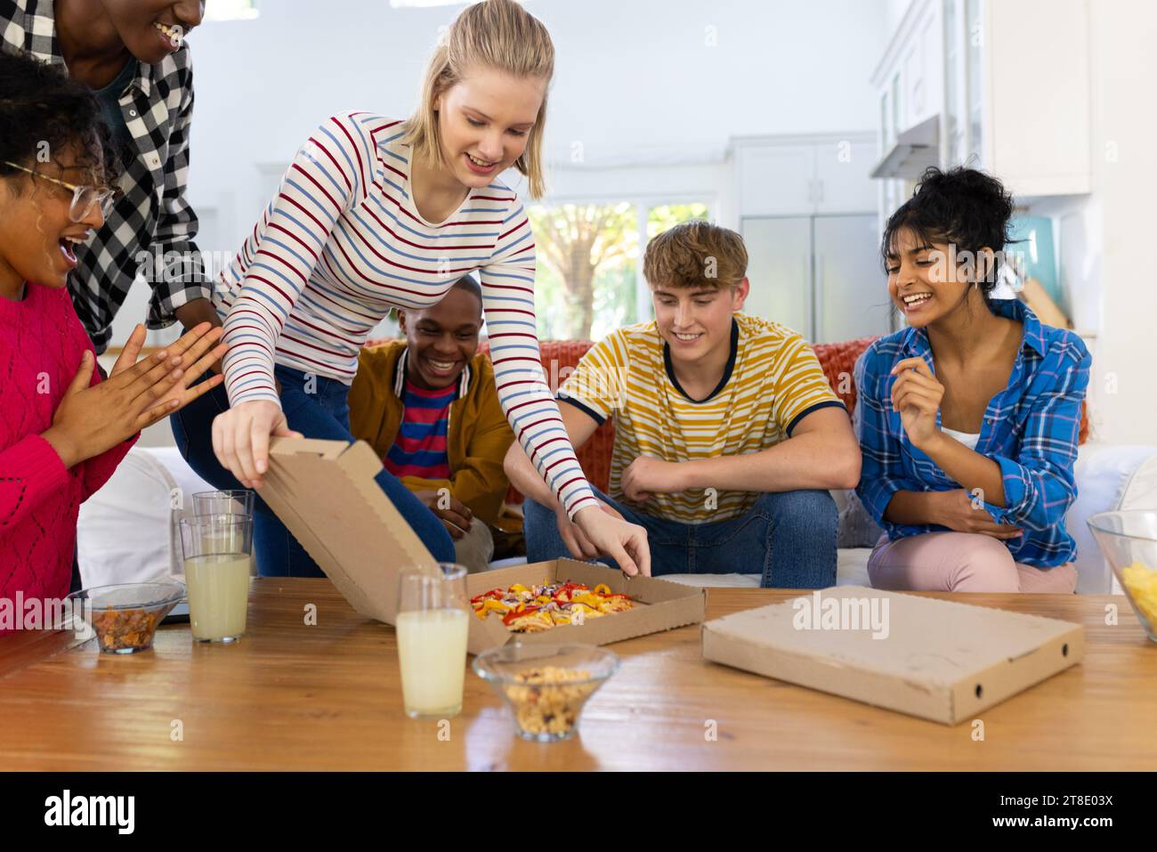 Heureux groupe diversifié d'amis adolescents assis sur le canapé et mangeant de la pizza Banque D'Images