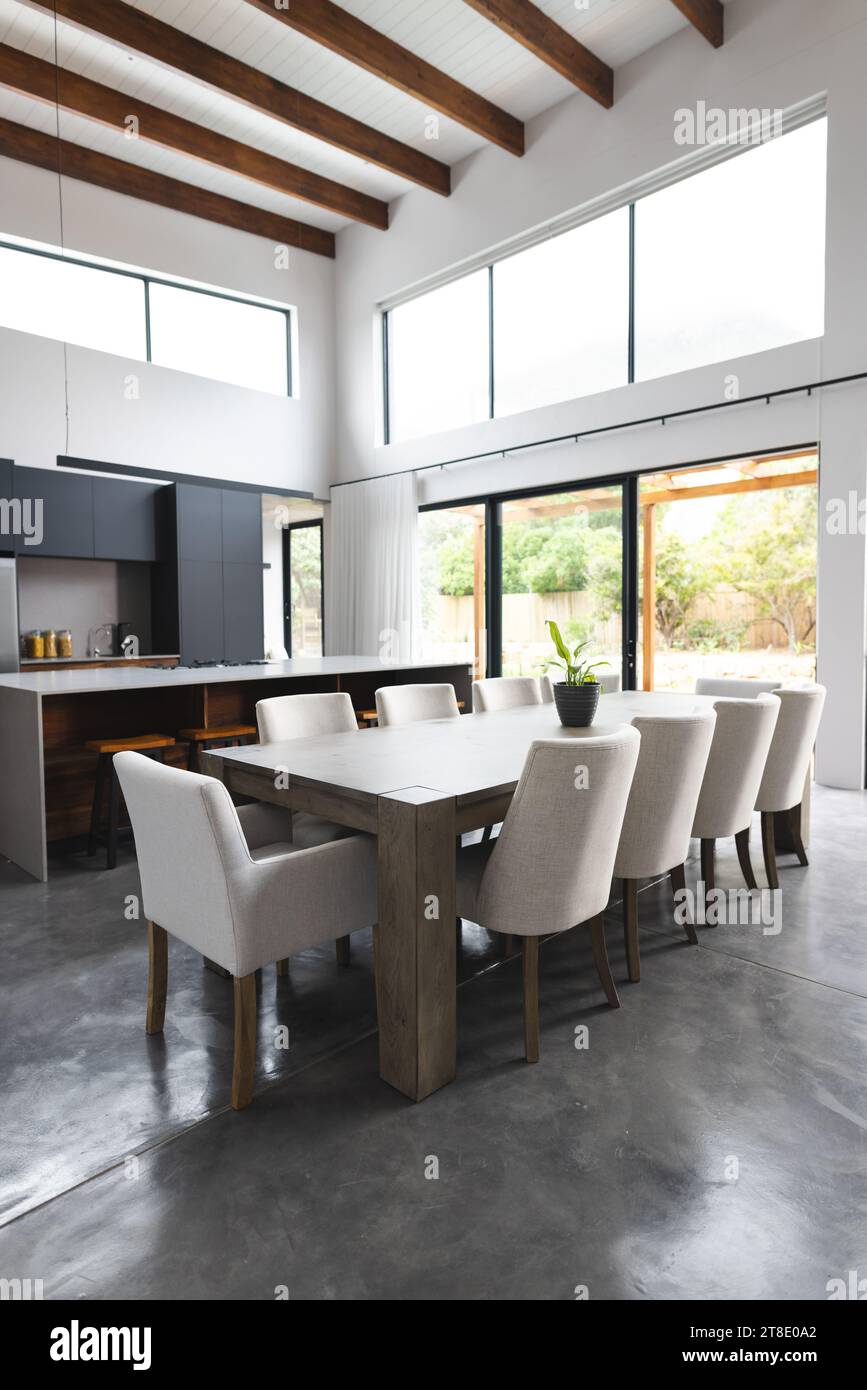 Grande cuisine vide avec table en bois, chaises blanches et grandes fenêtres Banque D'Images