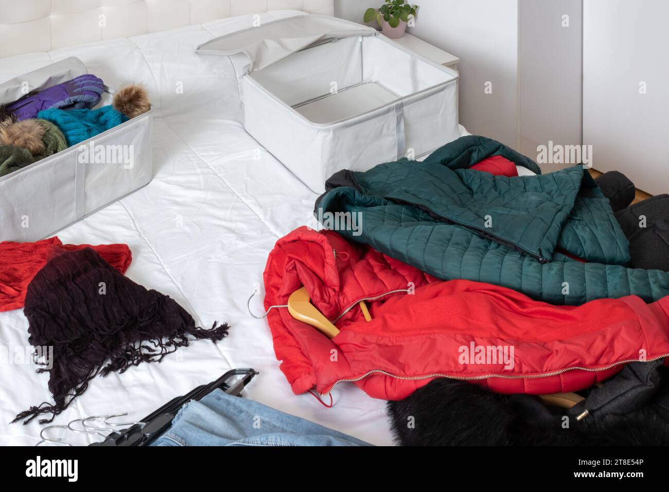 Photo horizontale, d'une pièce avec des vêtements d'hiver couchés sur le dessus du lit, à recueillir à l'intérieur des boîtes en tissu. Changer de placard. Banque D'Images