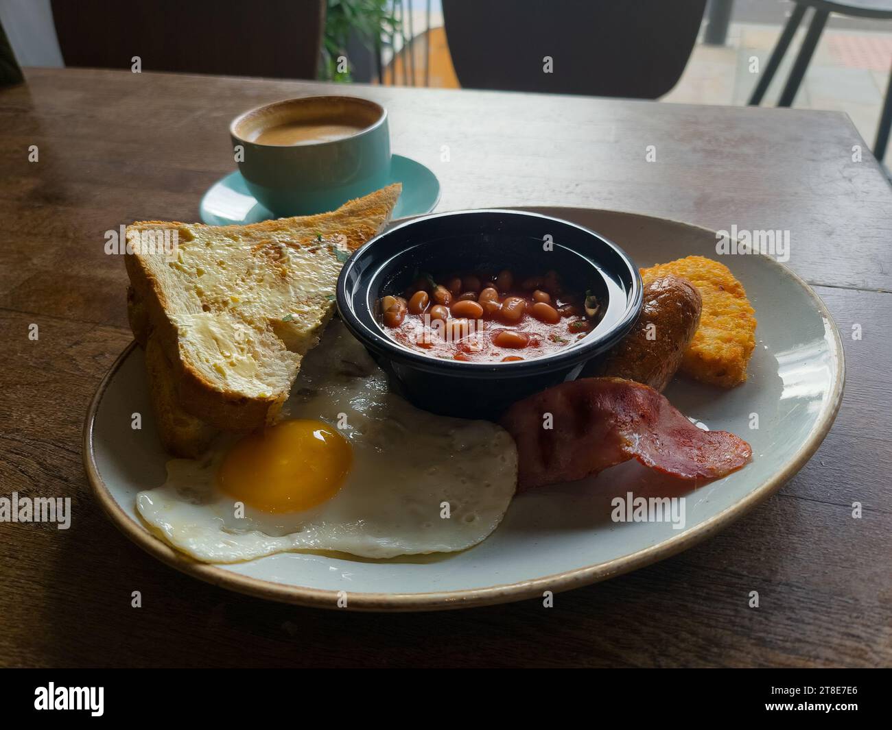 Petit-déjeuner anglais complet avec haricots et saucisses servis sur une table en bois Banque D'Images