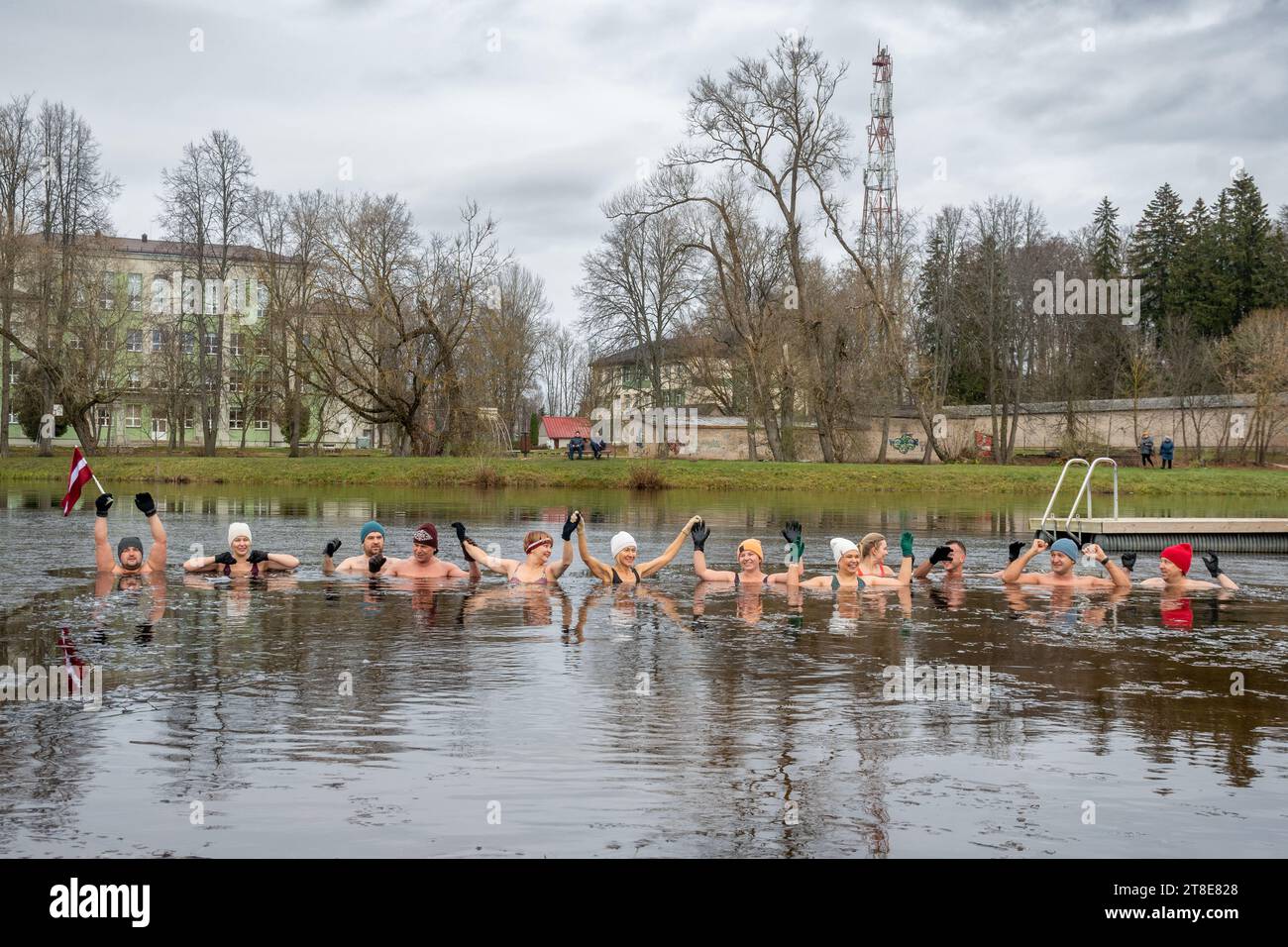 Groupe de personnes se baignant sur la glace ensemble dans l'eau froide d'un lac à Preili, Lettonie. Méthode Wim Hof, thérapie par le froid, techniques respiratoires, yoga Banque D'Images