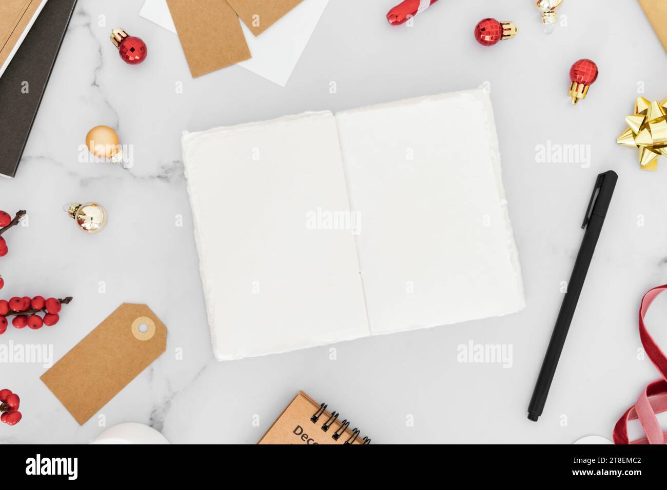 Cadre de Noël rouge à partir de décorations, paquet cadeau, bougies et cahier vierge ouvert sur fond de table blanc. Noël, nouvel an, concept d'hiver. FL Banque D'Images