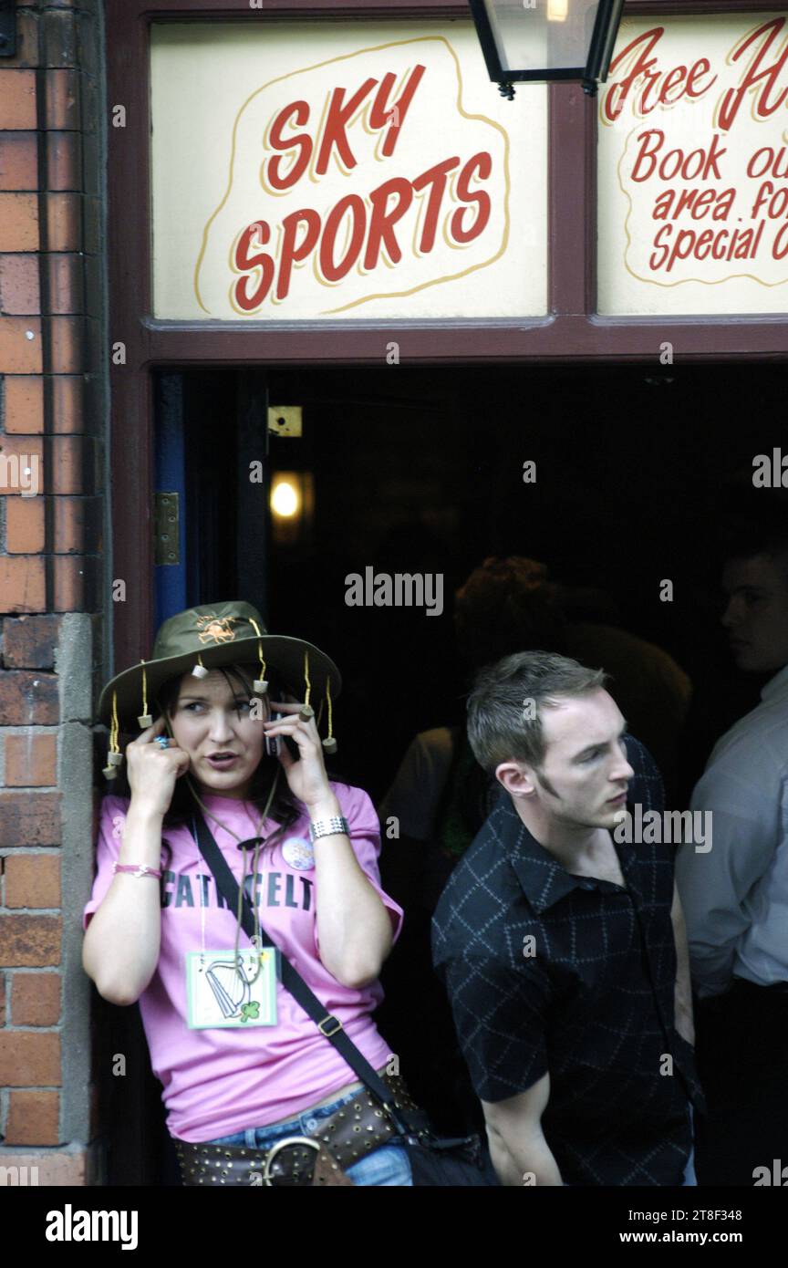 Un fan dans la porte d'un pub irlandais avec un chapeau de liège australien sur un téléphone portable flip à la mode ancienne devant le décideur du Grand Chelem dans les 2005 six Nations dans les rues de Cardiff, mars 19 2005. Le pays de Galles remporte le match 32–20 et le Grand Chelem. Photo : ROB WATKINS Banque D'Images