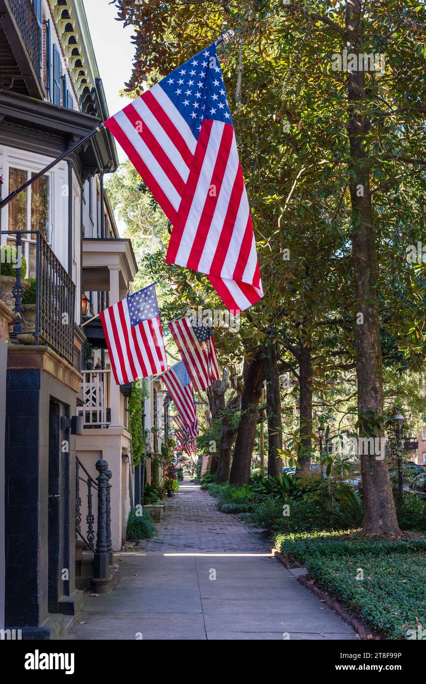 Savannah rue résidentielle et trottoir avec des drapeaux américains suspendus aux maisons dans le quartier historique, Géorgie, États-Unis. Banque D'Images