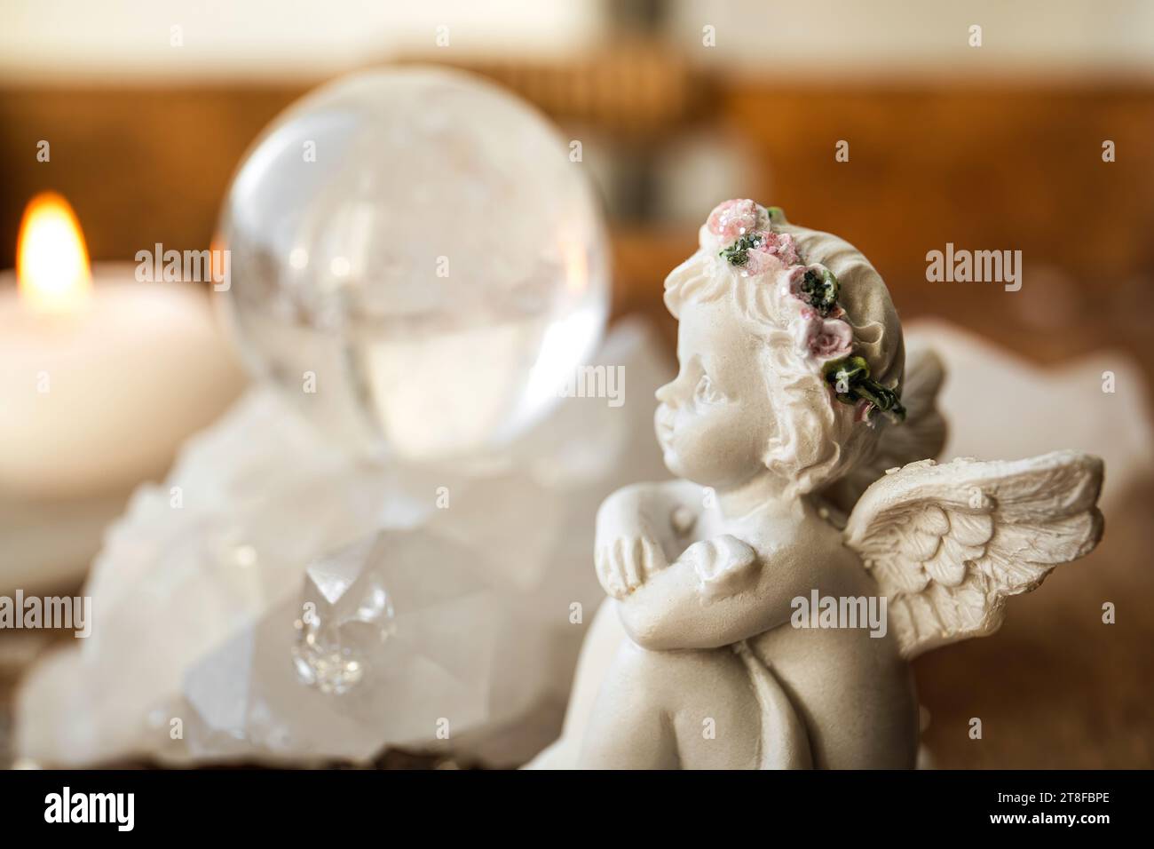 Concept de message d'ange spirituel. Petite figurine d'ange mignon assis par boule de pierre précieuse de cristal dans la maison à l'intérieur. Banque D'Images