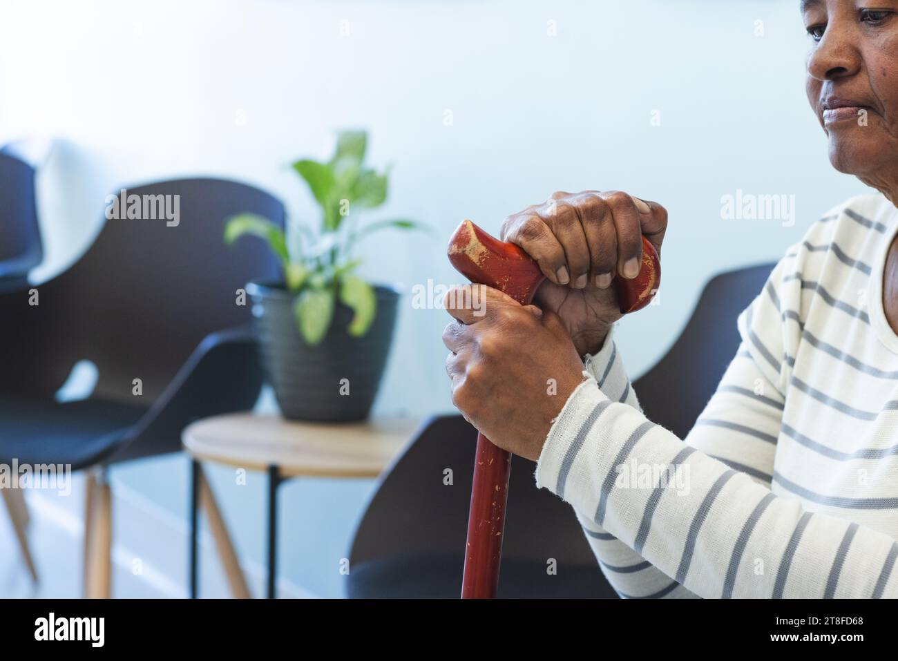 Femme aînée afro-américaine avec bâton de marche assis dans la salle d'attente d'un hôpital Banque D'Images