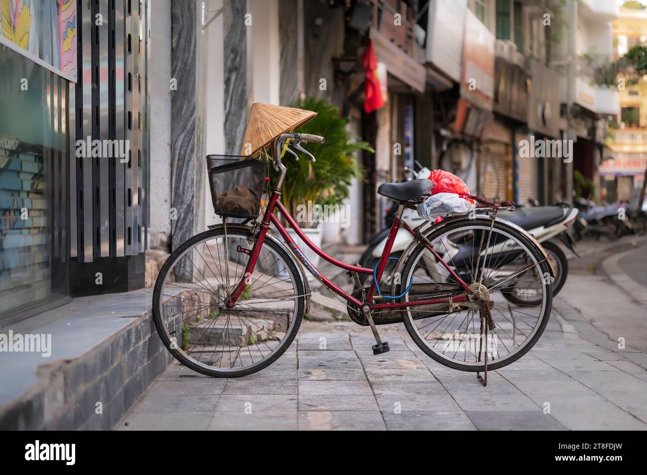 Un bycicle, garé dans une rue vietnamienne, avec un chapeau conique traditionnel équilibré sur le guidon Banque D'Images