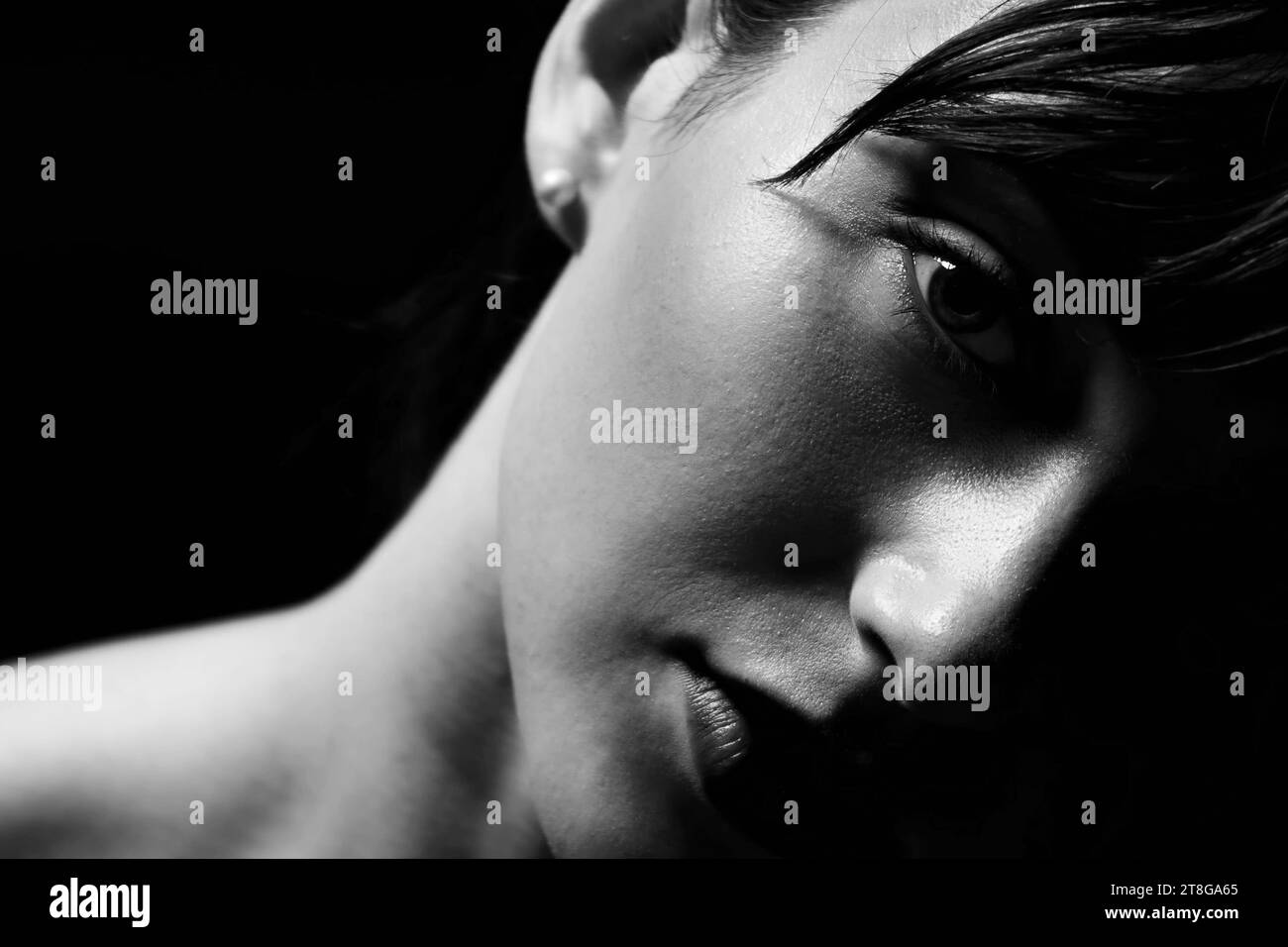 Unseeing Eyes - un portrait noir et blanc en gros plan d'une jeune femme aux cheveux foncés regardant dans le vide. Banque D'Images