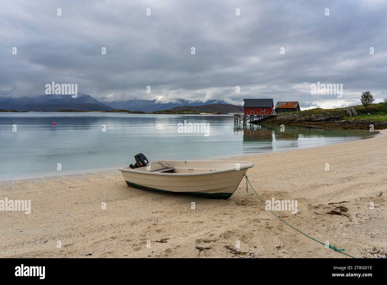 Bateau à rames près de la plage de sable blanc de Sommarøy à Troms, Norvège. En arrière-plan les eaux turquoises de l'Atlantique avec des îles et un hangar à bateaux Banque D'Images