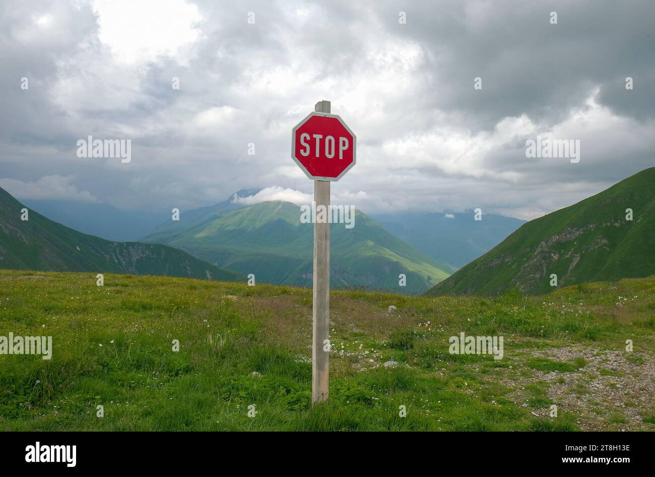 Panneau d'arrêt rouge contre le sommet des montagnes et les chaînes sous les nuages bas. Jour, été. Voie de choix ou concept de réchauffement climatique. Photo de haute qualité Banque D'Images