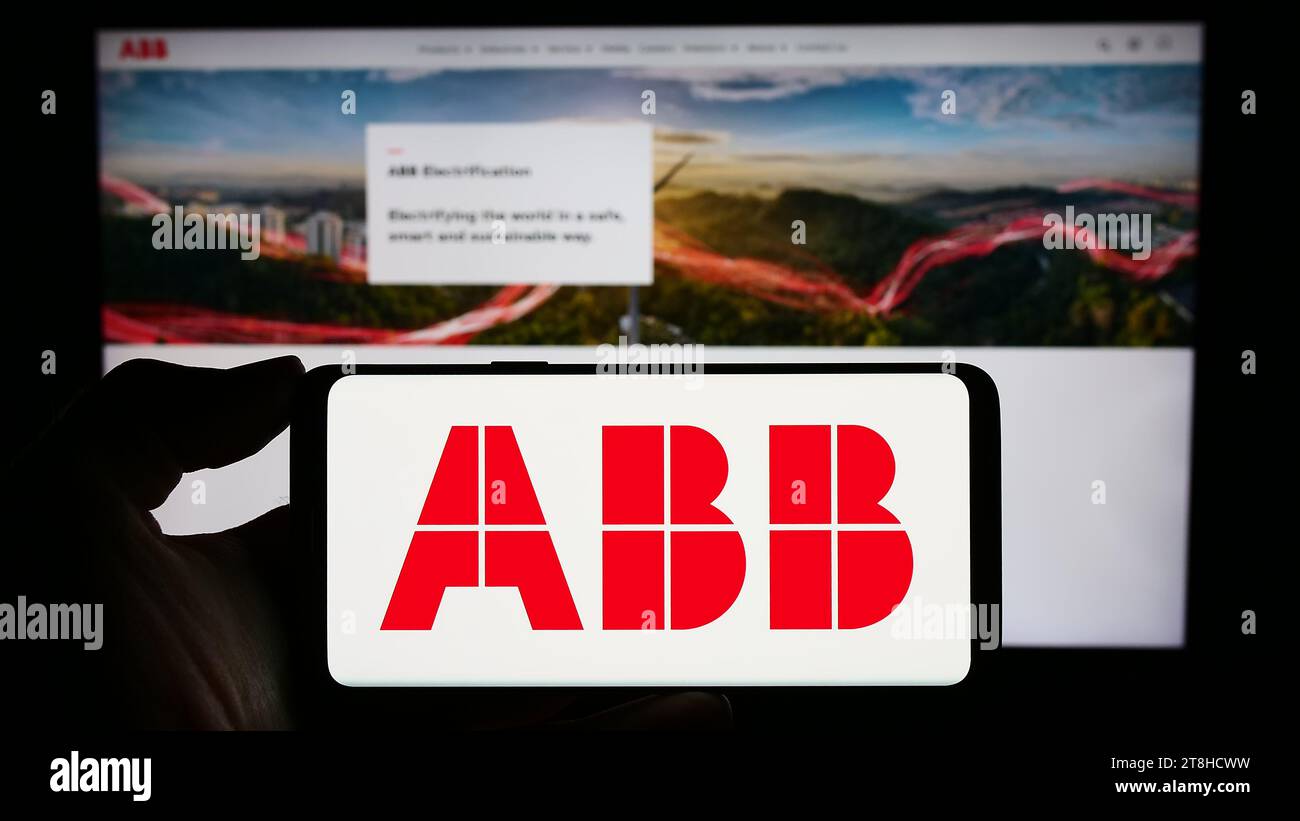 Personne détenant un téléphone cellulaire avec le logo de la société d'équipement électrique ABB Ltd. Devant la page Web de l'entreprise. Concentrez-vous sur l'affichage du téléphone. Banque D'Images