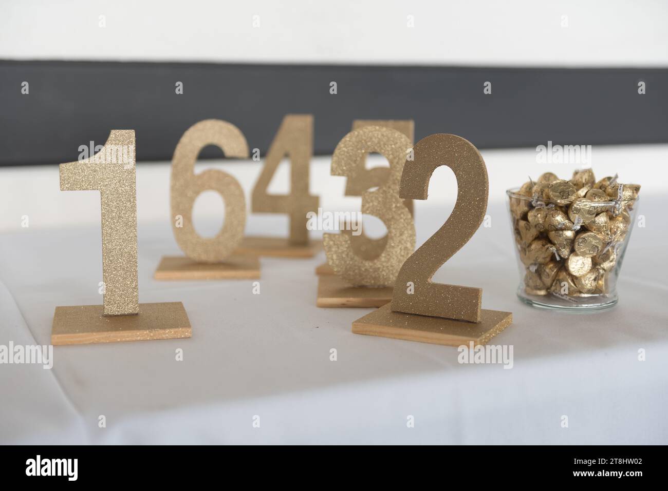 Trois panneaux de numéro de table en métal doré disposés sur une surface blanche Banque D'Images