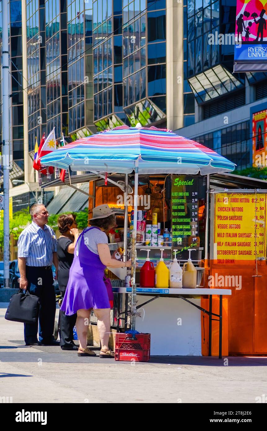 TORONTO, CANADA, les gens achètent de la restauration rapide dans un stand de hot-dogs à Yonge-Dundas Square Banque D'Images