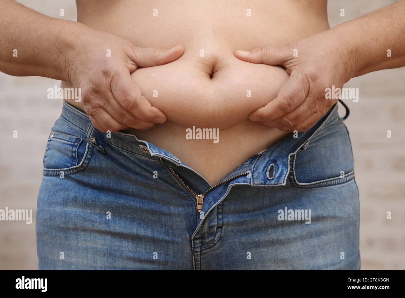 femme montrant sa graisse du ventre et ne peut pas fermer son jean Banque D'Images