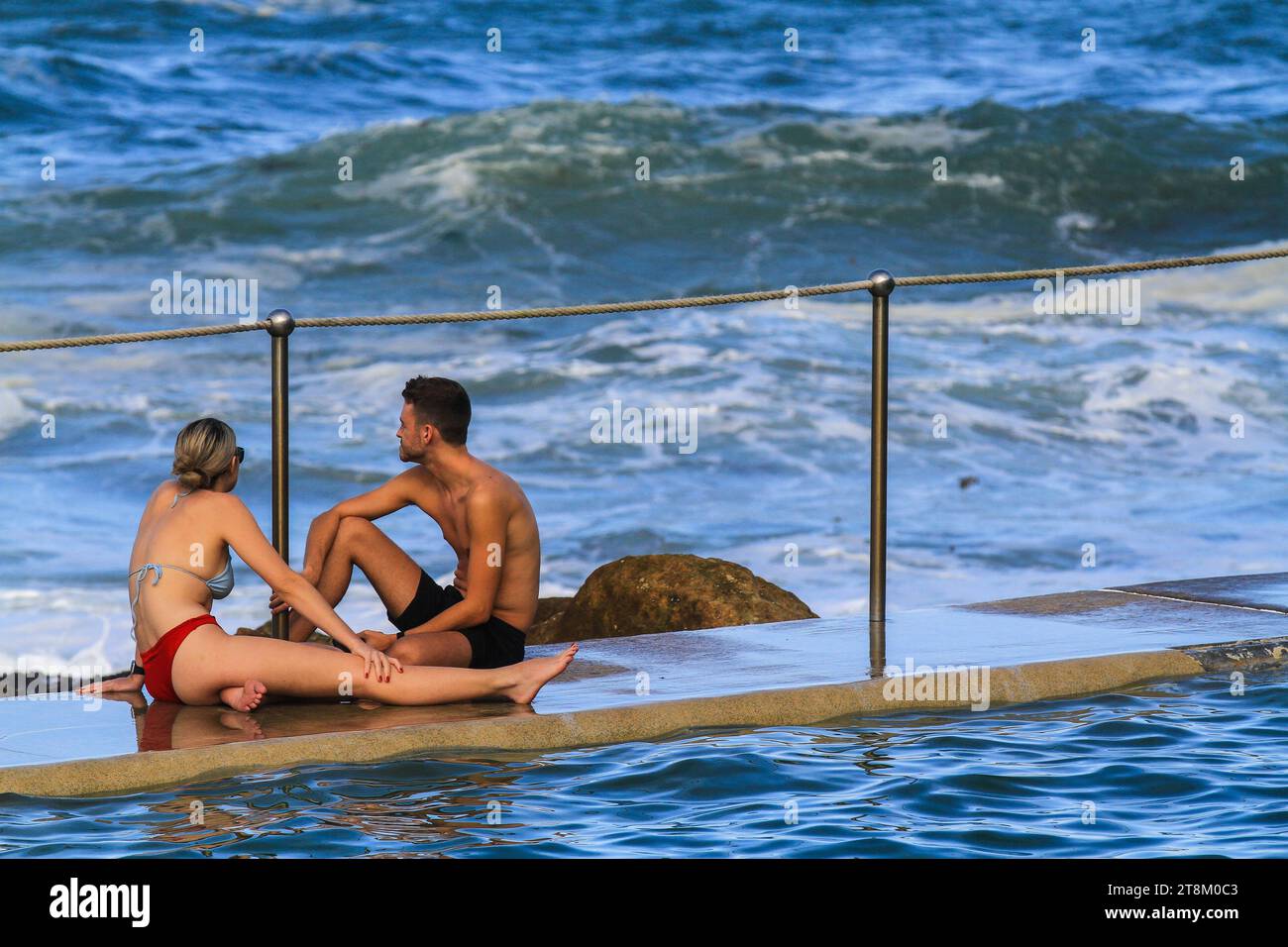 Un jeune couple s'assoit au bord de la piscine de Bronte. Banque D'Images