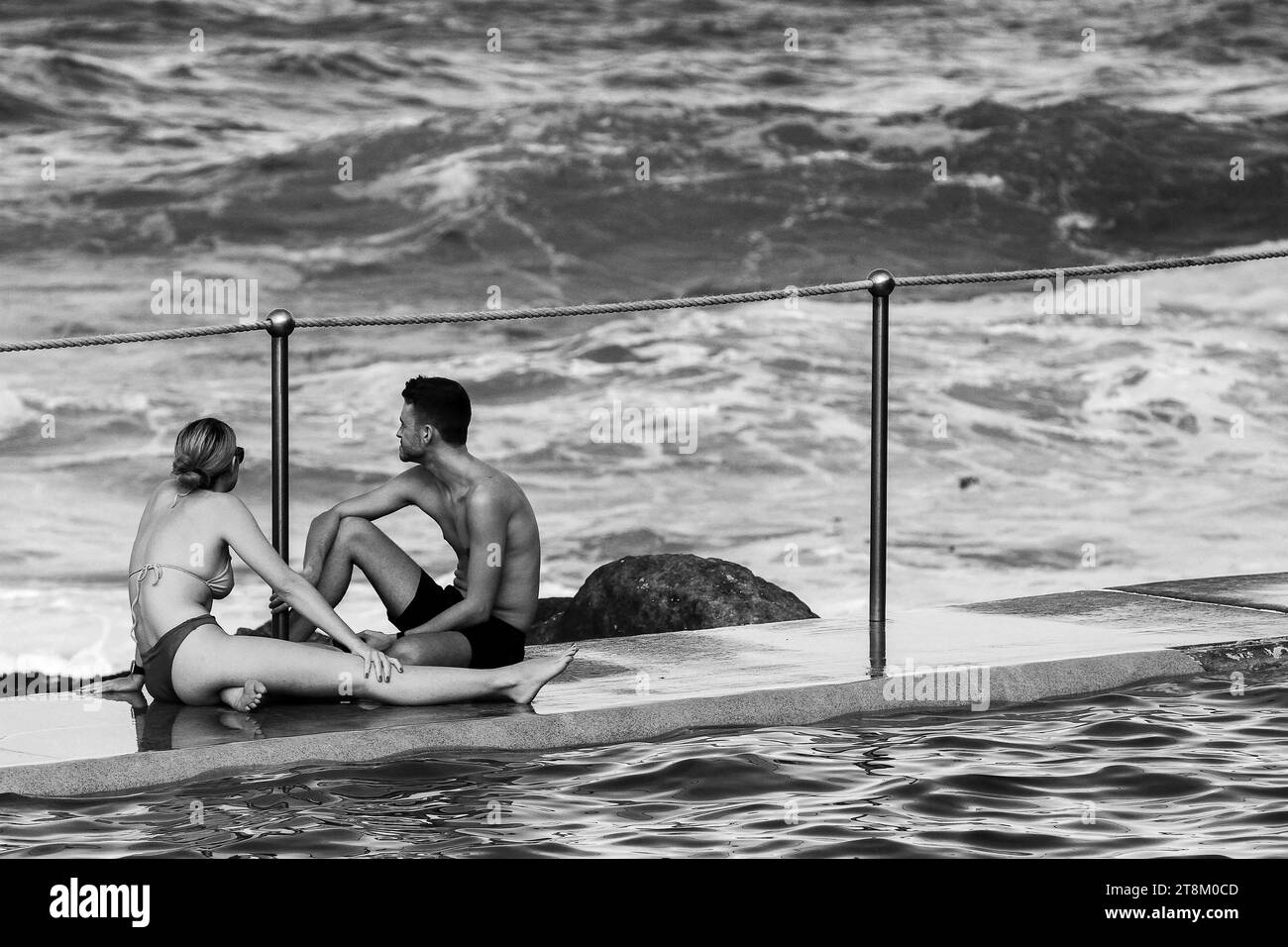Un jeune couple s'assoit au bord de la piscine de Bronte. Banque D'Images