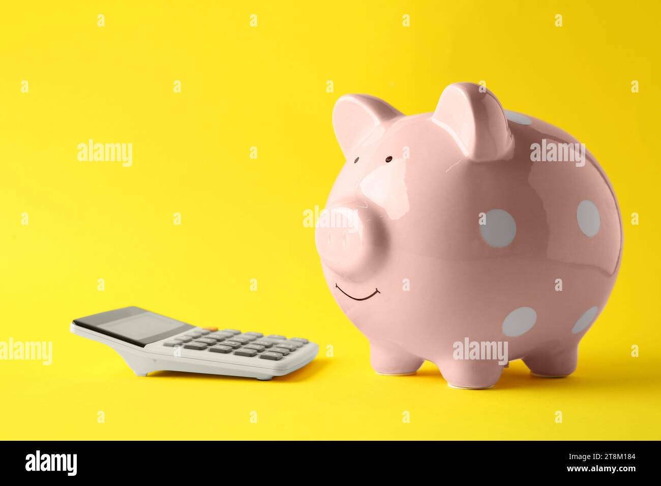 Calculatrice et tirelire rose sur fond jaune Banque D'Images