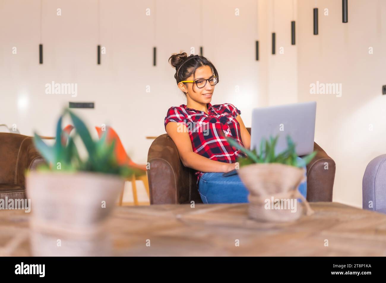 Jeune femme entrepreneure travaillant à domicile en utilisant un ordinateur portable assis dans un canapé confortable Banque D'Images