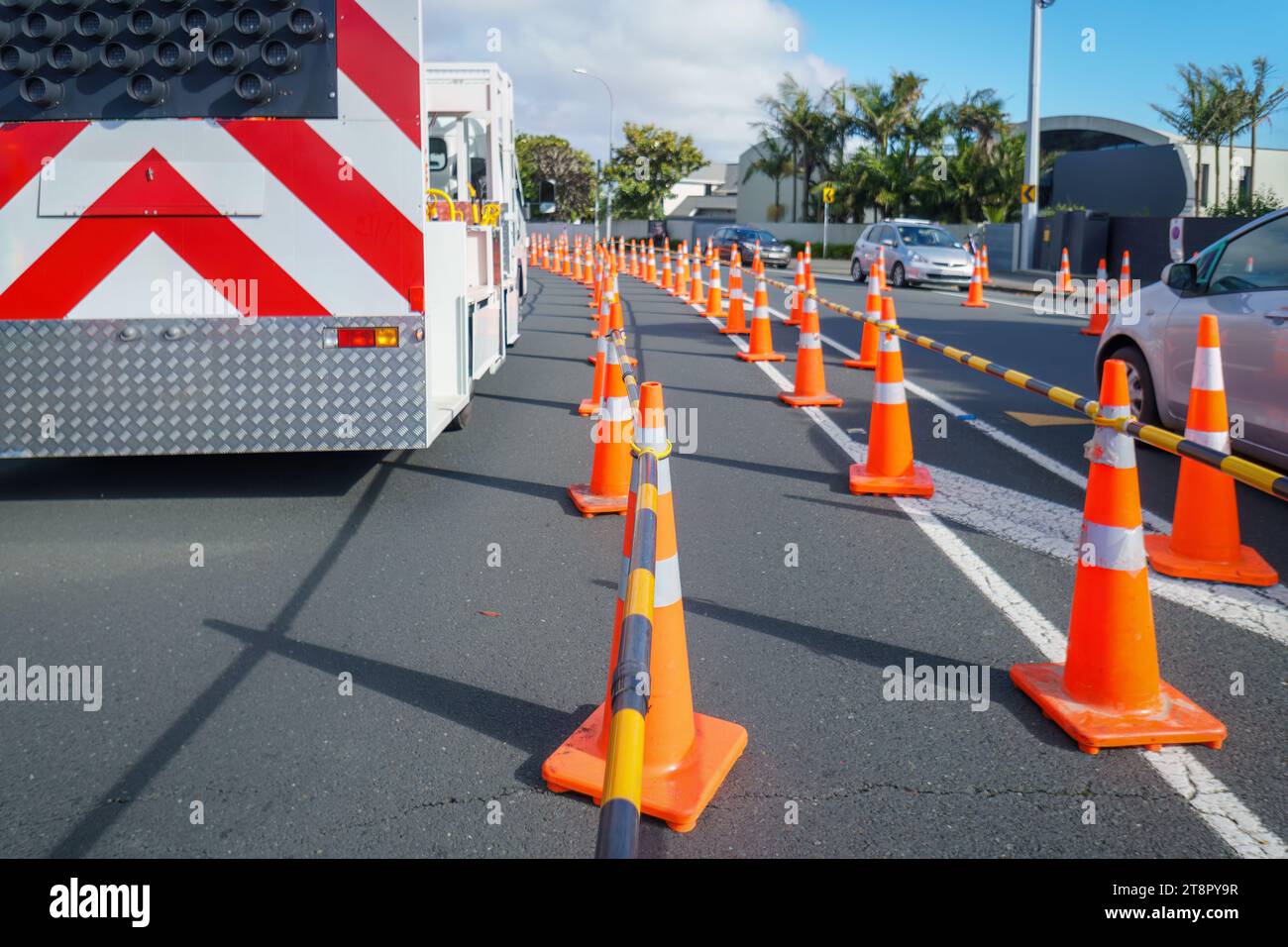 Camion de travail et cônes de signalisation orange dans la rue. Voitures circulant sur la route restreinte. Travaux routiers à Auckland. Banque D'Images