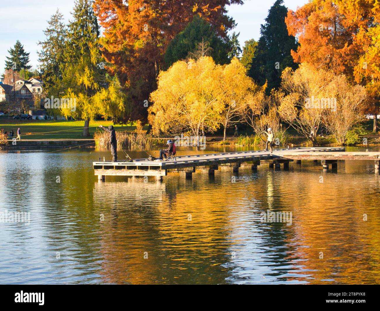 Chiffres sur la jetée du lac dans la distance sur la journée ensoleillée d'automne faisant des loisirs de pêche sportive en plein air à Green Lake Park à Seattle, Washington. Banque D'Images