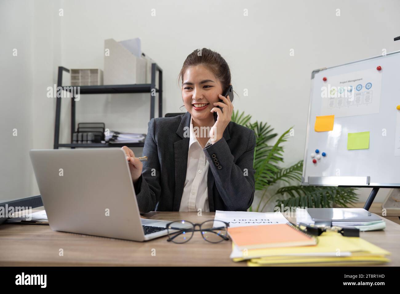 Joyeuse jeune femme d'affaires asiatique parlant au téléphone travaillant dans le bureau. Heureuse positive chef d'entreprise asiatique de femme d'affaires portant costume faisant appel Banque D'Images