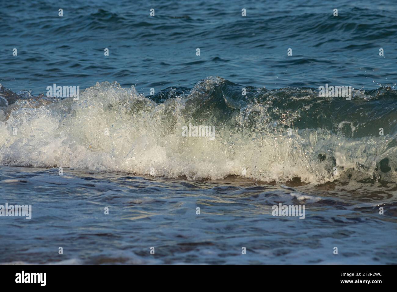 Une grande et forte onde de tempête de couleur turquoise avec des éclaboussures de mousse blanche coule et se brise sur le rivage. Banque D'Images
