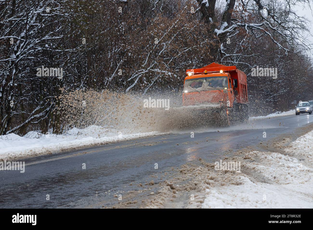 Une grande voiture avec une charrue dégage la route de la neige. L'équipement spécial Orange CARGO rencontre des difficultés avec les éléments en hiver. Suppression des effets de t Banque D'Images