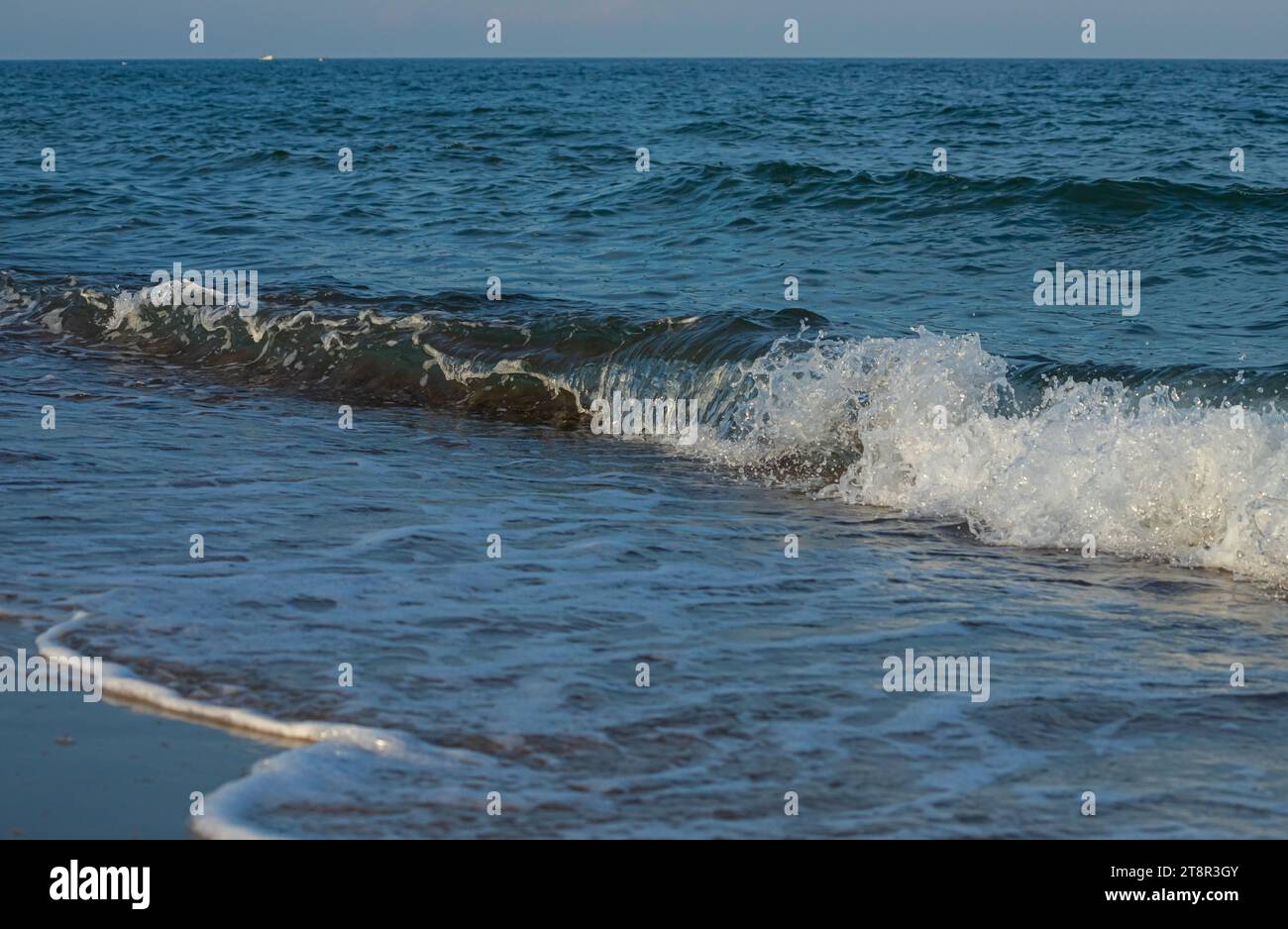 Une grande et forte onde de tempête de couleur turquoise avec des éclaboussures de mousse blanche coule et se brise sur le rivage. Banque D'Images
