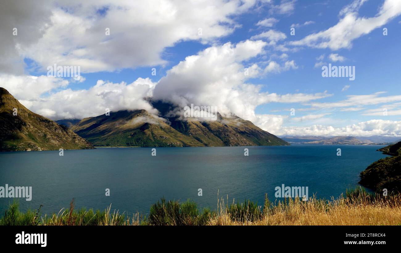 Lac Wakatipu. NZ, le deuxième plus grand des lacs glaciaires du sud, le lac Wakatipu mesure 48 miles de long et jusqu'à 3 miles de large, et couvre une superficie de 113 miles carrés. Le lac est à 1 017 pieds au-dessus du niveau de la mer, est de 1 239 pieds de profondeur, et occupe une tranchée glaciaire allongée ayant un fond plat en pente douce (probablement en raison d'un remplissage de sédiments fins). Contrairement au lac te Anau, Wakatipu a une apparence plus stérile en raison du manque de forêt sur la majeure partie de ses 1 150 miles carrés de drainage. Il est bordé de tous côtés par des montagnes glaciaires, dont la plus haute est le mont Earnslaw Banque D'Images