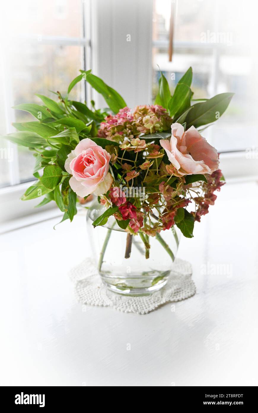 Vase décoratif d'arrangement de fleurs d'automne comprenant des roses roses et des fleurs d'Hydrangea dans une baie vitrée avec la lumière naturelle Banque D'Images