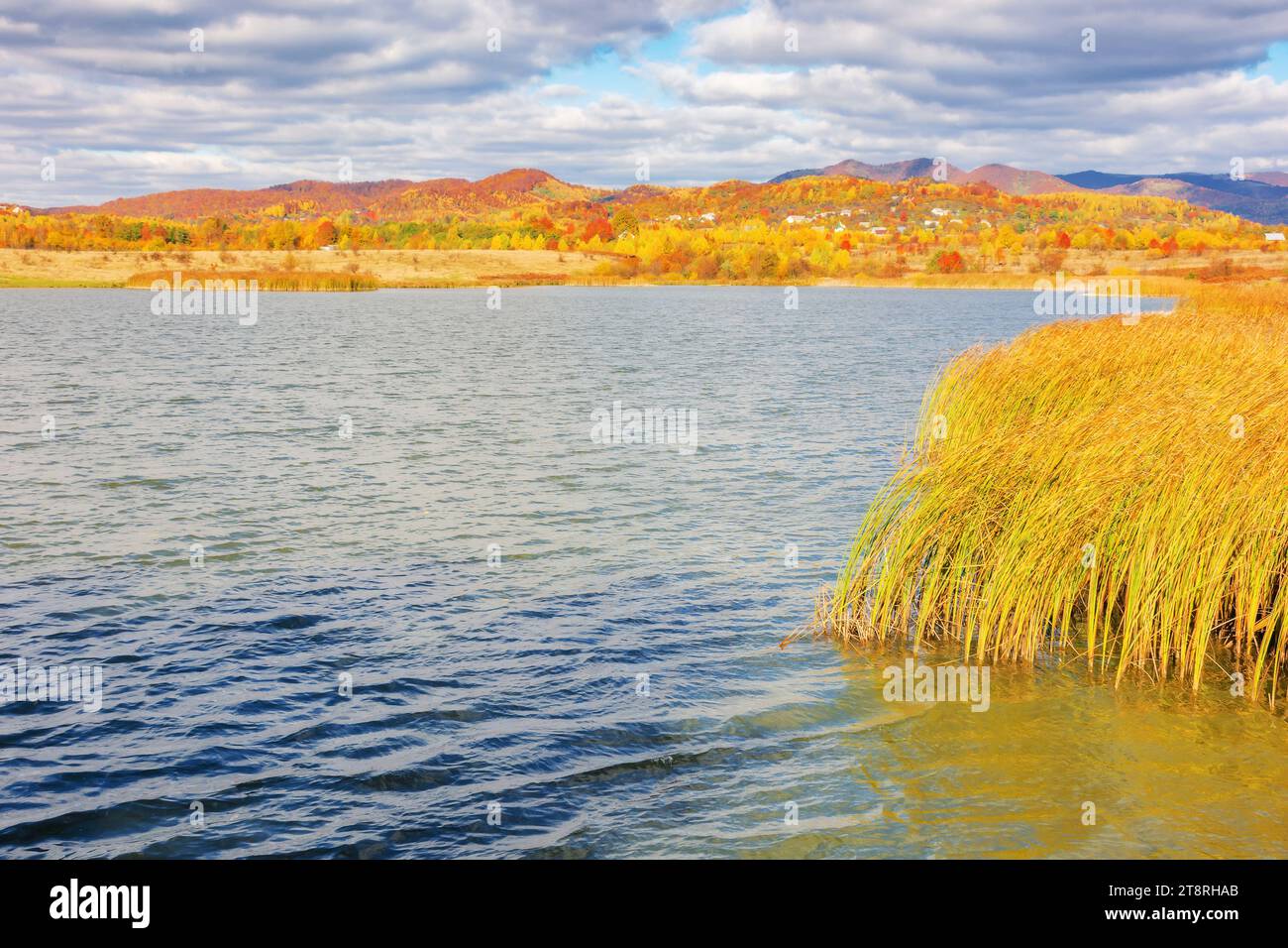 paysage montagneux avec lac de pêche en automne. beau paysage de campagne avec village sur l'autre rive. journée ensoleillée avec nuages sur le ciel Banque D'Images