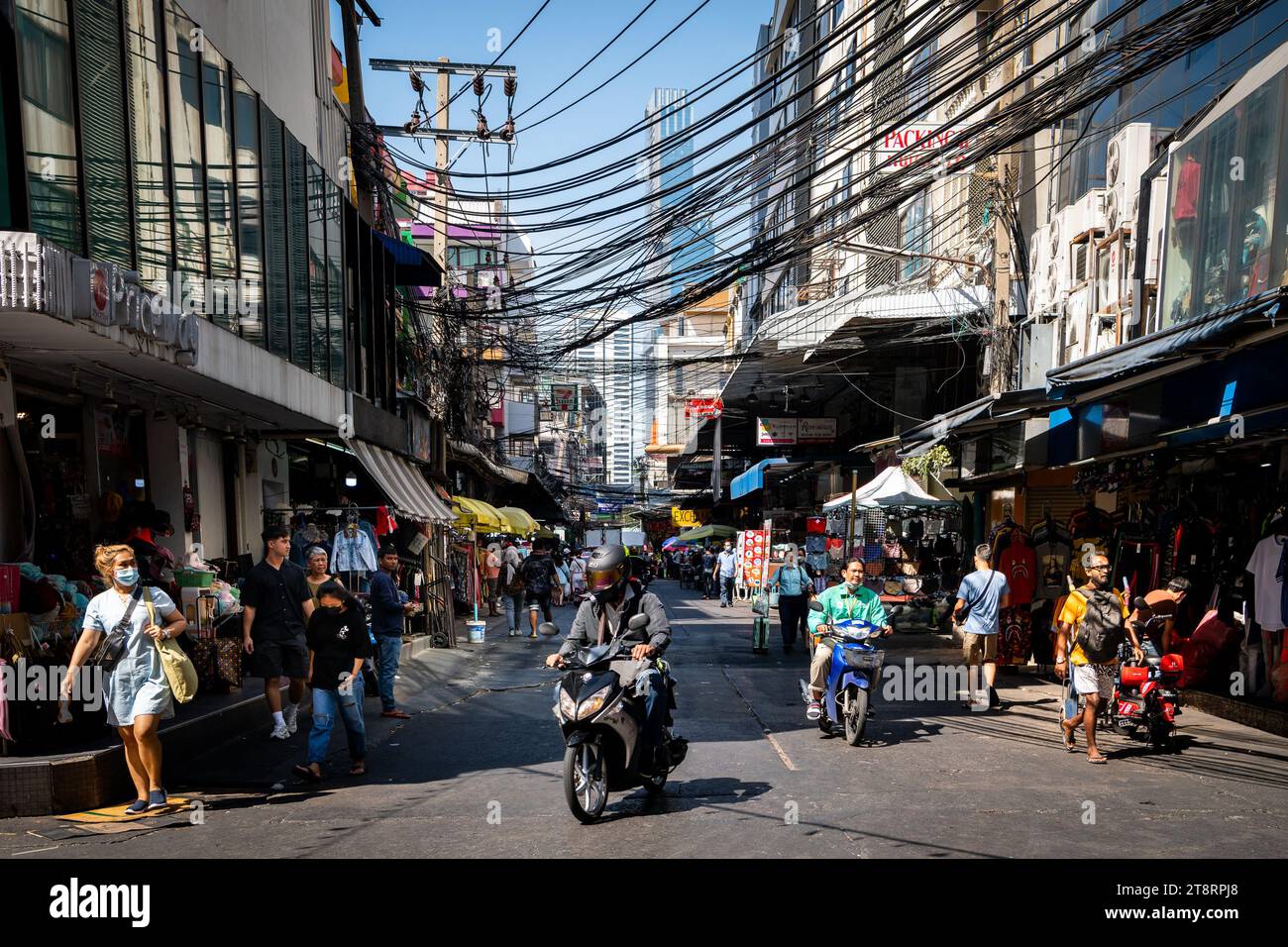 Une moto fait son chemin à travers les rues animées du marché de Pratunam, Bangkok, Thaïlande. Banque D'Images