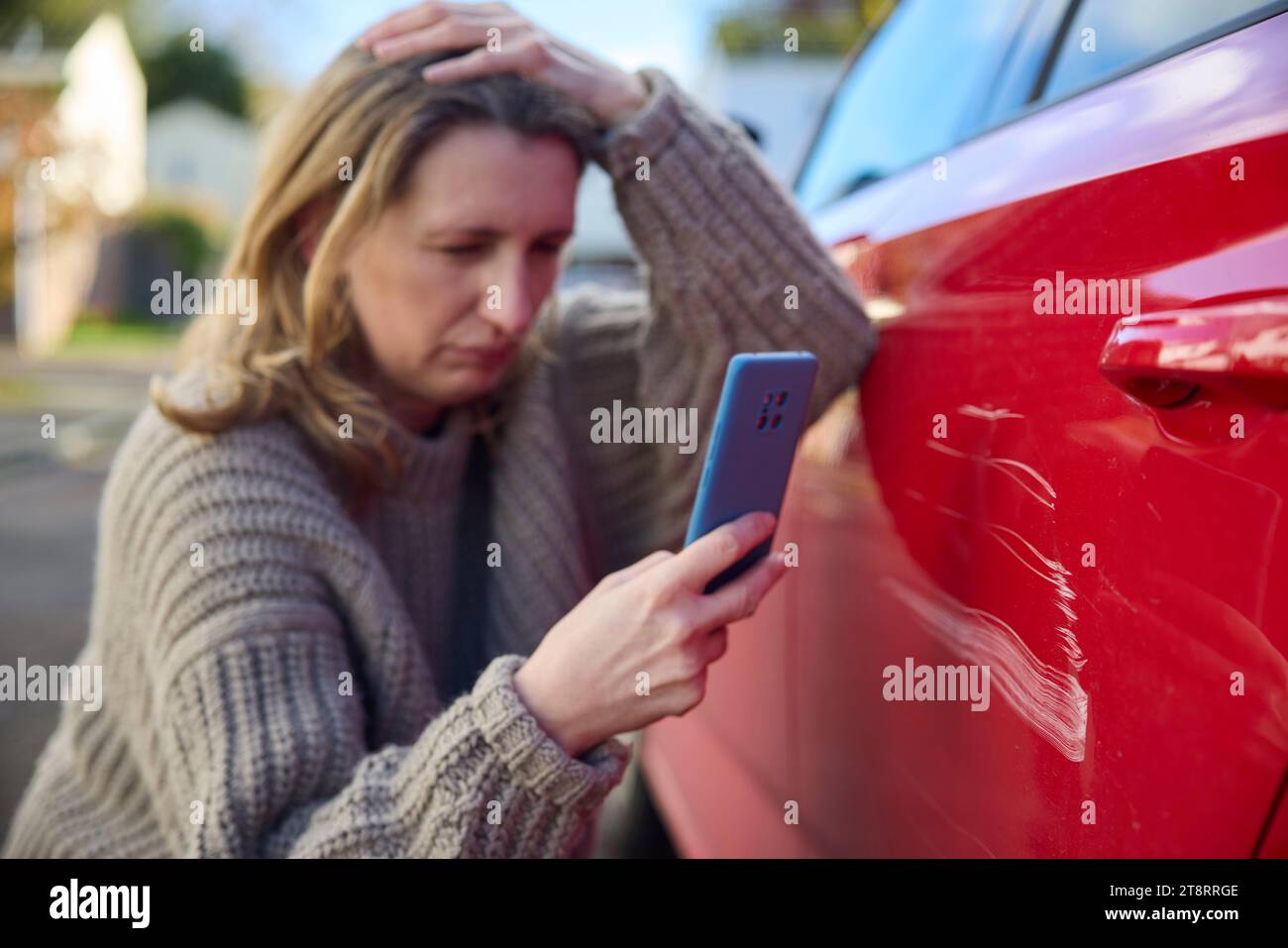 Malheureux conducteur mature Femme prenant photo de dommages à la voiture après accident sur téléphone portable Banque D'Images