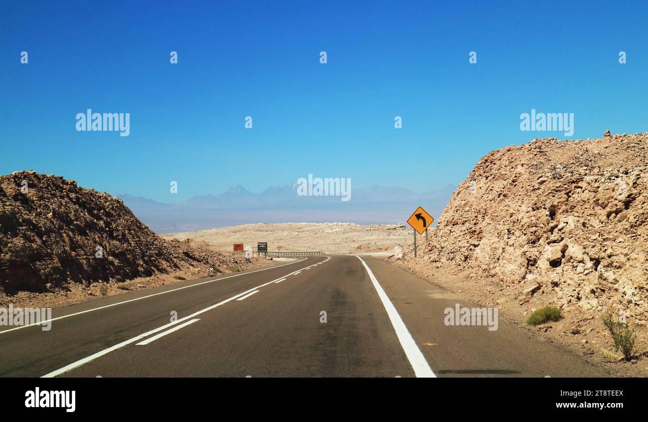 Route vide dans le désert d'Atacama avec le panneau de signalisation de virage à gauche, réserve nationale de Los Flamencos, nord du Chili, Amérique du Sud Banque D'Images