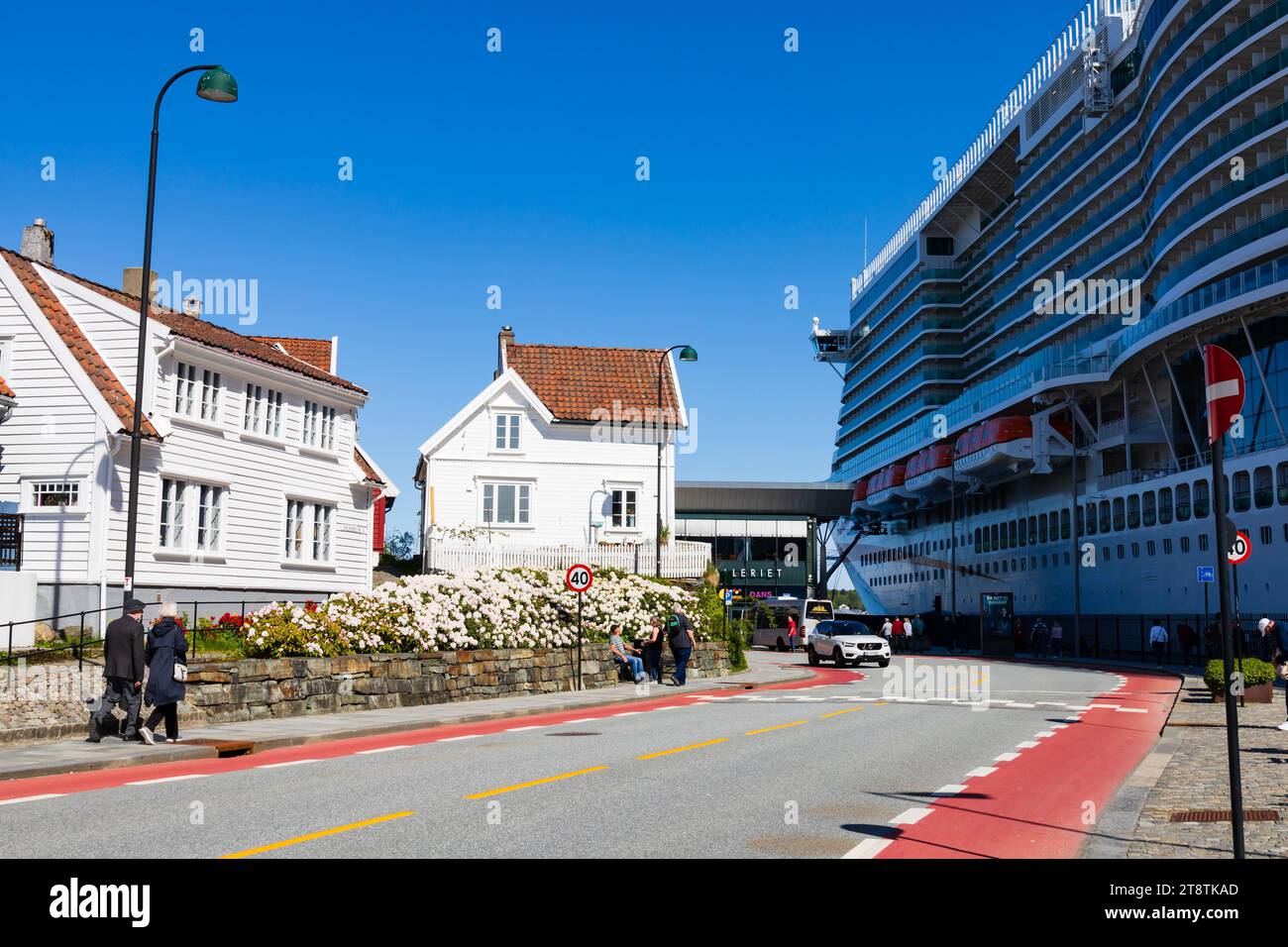 Maison traditionnelle en bois blanc éclipsée par la visite d'un grand navire de croisière, le MS Iona, sur le quai. Nerde Strandgate, avec des gens walking.Stavanger, Norw Banque D'Images