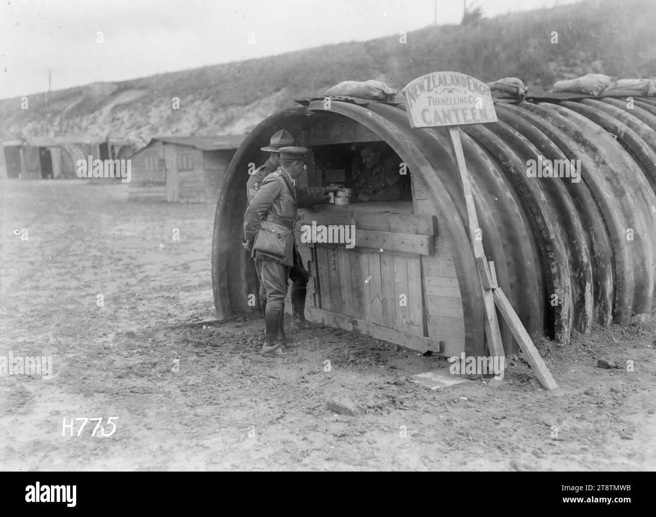 La cantine de la New Zealand Engineers Tunnelling Company à Dainville, pendant la première Guerre mondiale, deux soldats achètent des articles au comptoir de la cantine de la New Zealand Engineers Tunnelling Company à Dainville, en France pendant la première Guerre mondiale La structure en fer ondulé semi-circulaire basse avec une façade en bois peut être une ancienne hutte Nissen. Photographie prise le 16 juillet 1918 Banque D'Images